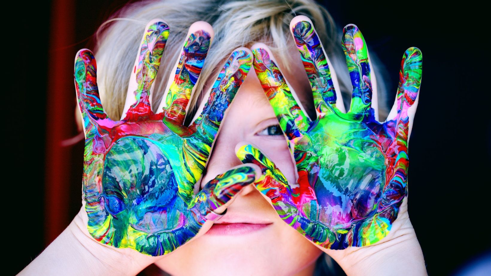 A boy whose hands are covered in paint